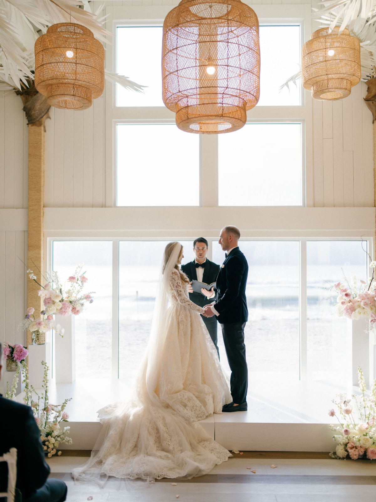 Bride and groom at ceremony in front of floor to ceiling windows