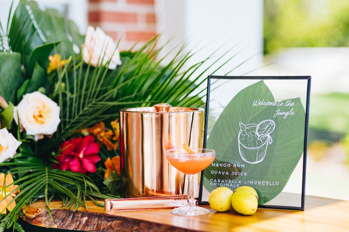 Close-up of bar menu, cocktail, and tropical flower arrangement