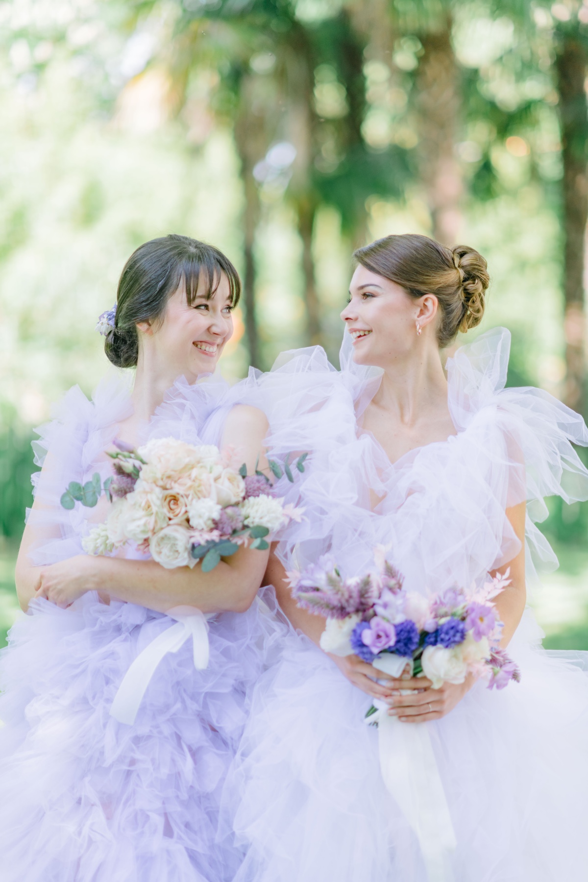 Portrait of bride and bridesmaid in tulle dresses holding bouquets