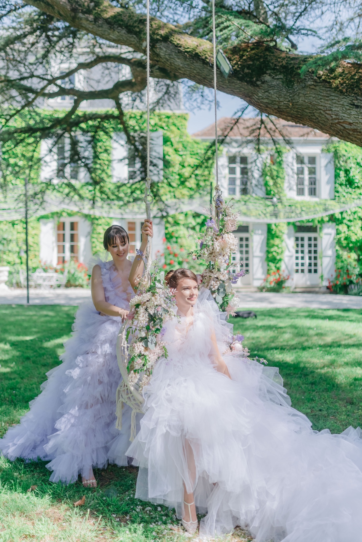 Bride and bridesmaid in tulle dresses on decorated swing