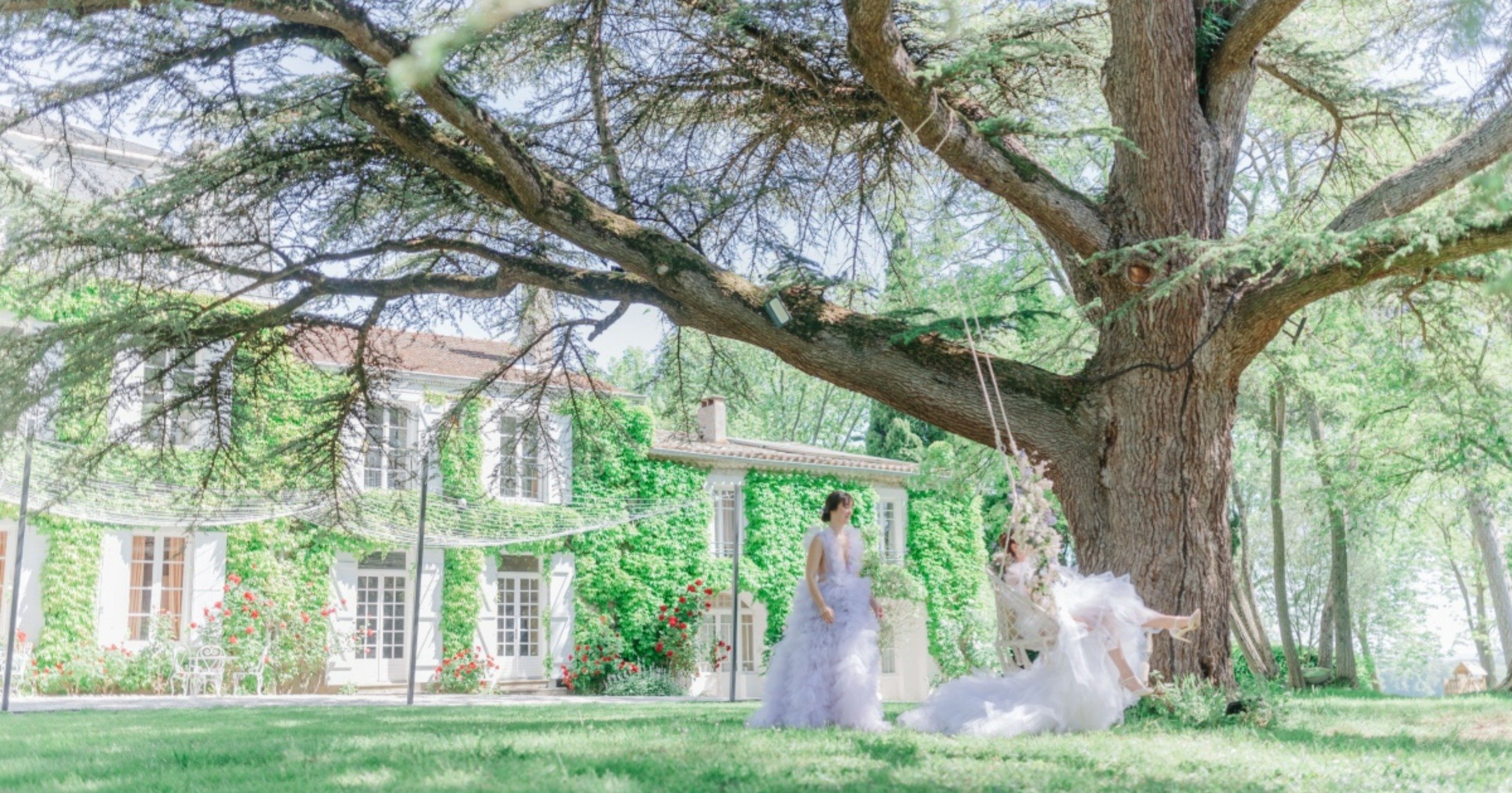 Two brides in front of estate with one bride on decorated swing