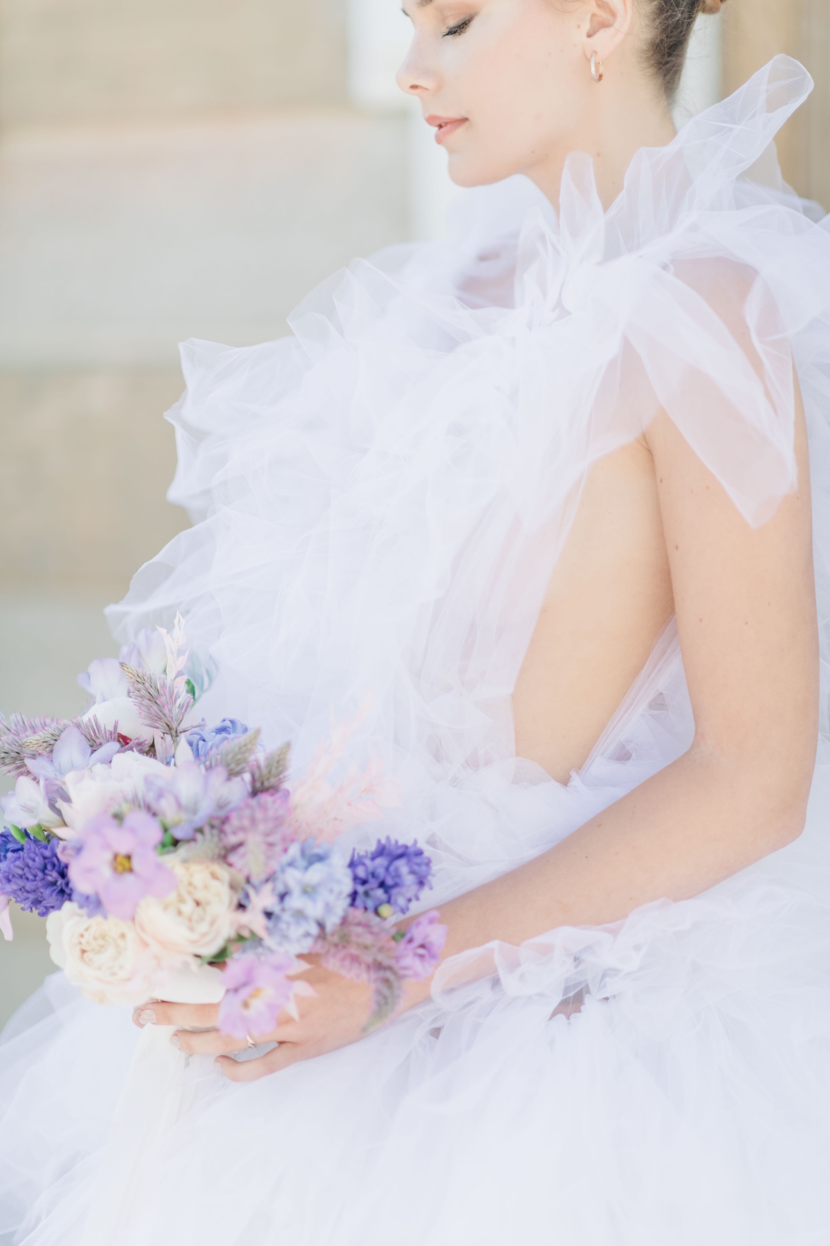 Side portrait of bride holding lilac bouquet