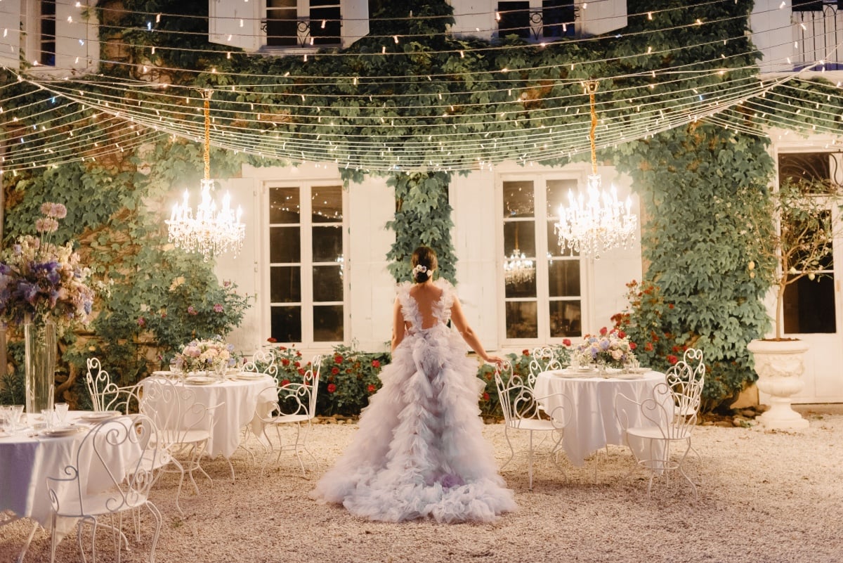 Bride in reception area at night with string lights and chandeliers lit up