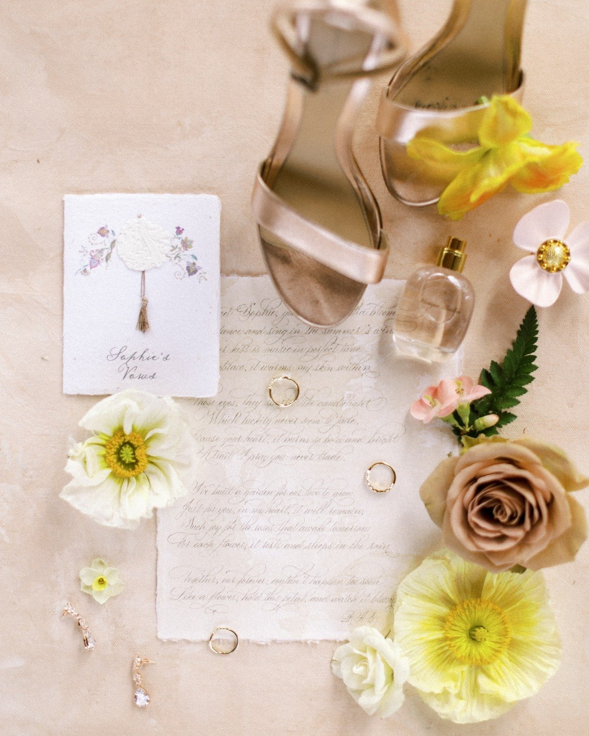 Aerial view of vows, wedding rings, and bridal shoes with flowers surrounding