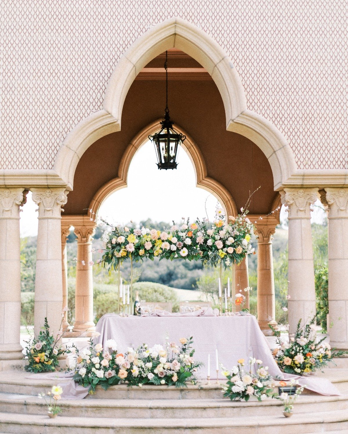 Sweetheart table for reception covered in floral arrangements and tapered candles