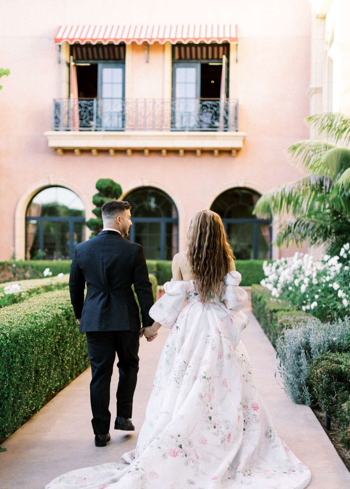 Portrait of bride and groom walking away towards villa