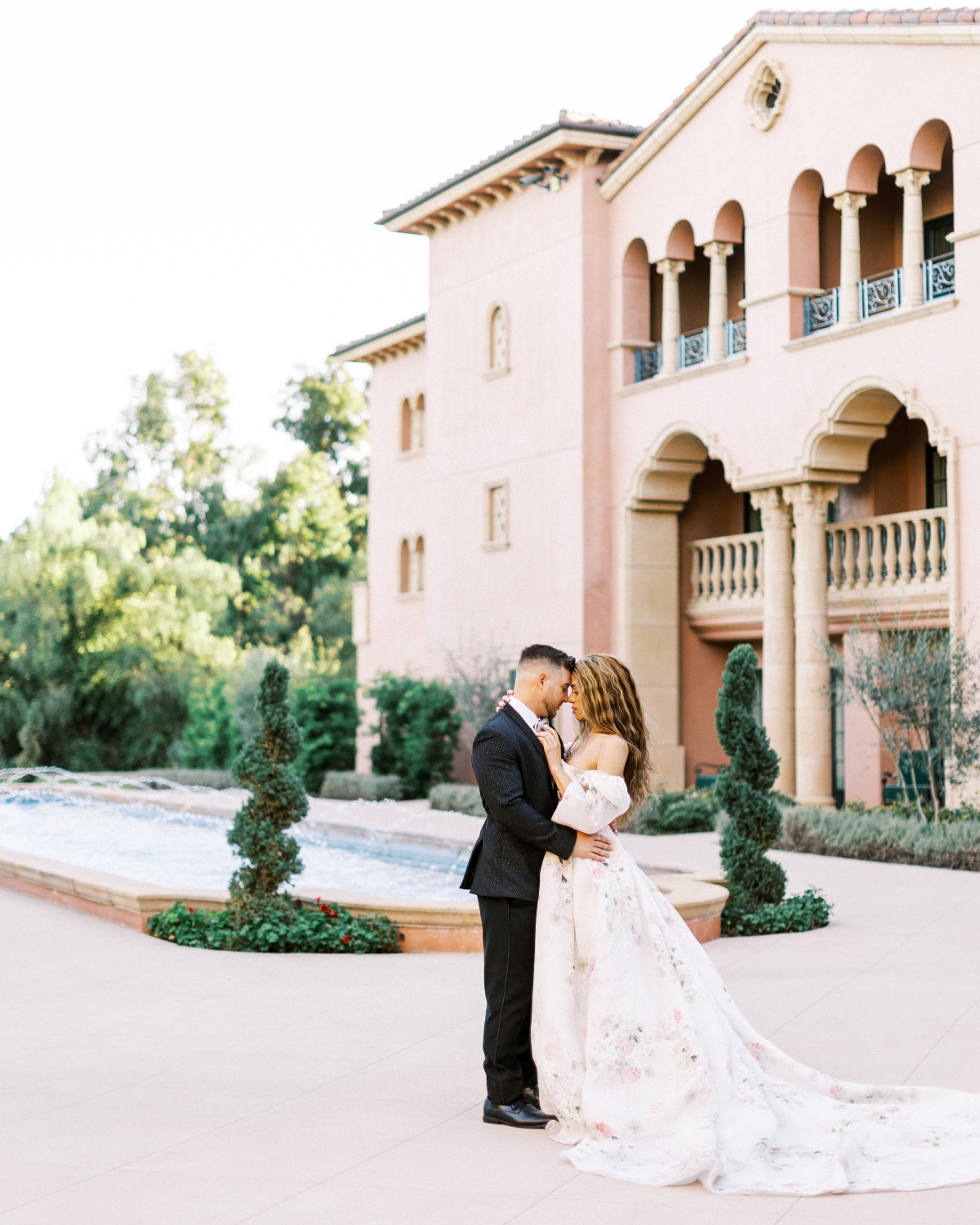 Bride and groom in front of fountain and villa