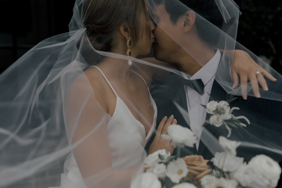 View of bride and groom kissing through veil