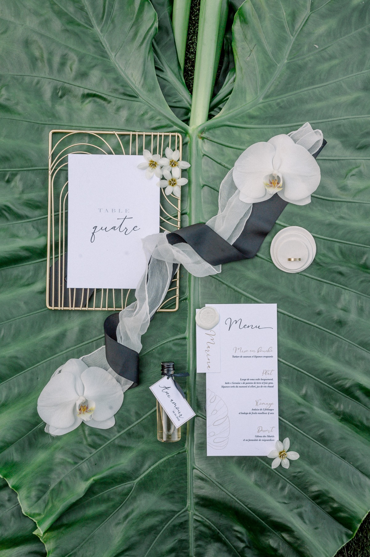 Aerial photo of menu, sashes, and table number on banana leaf