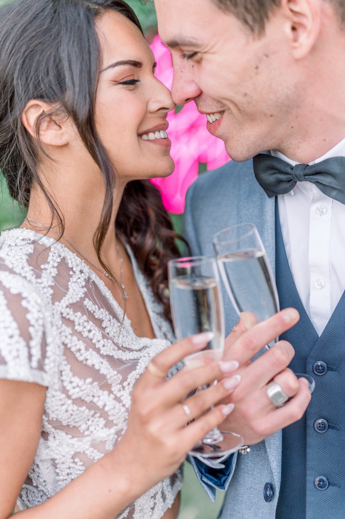 Bride and groom nose to nose holding champagne glasses
