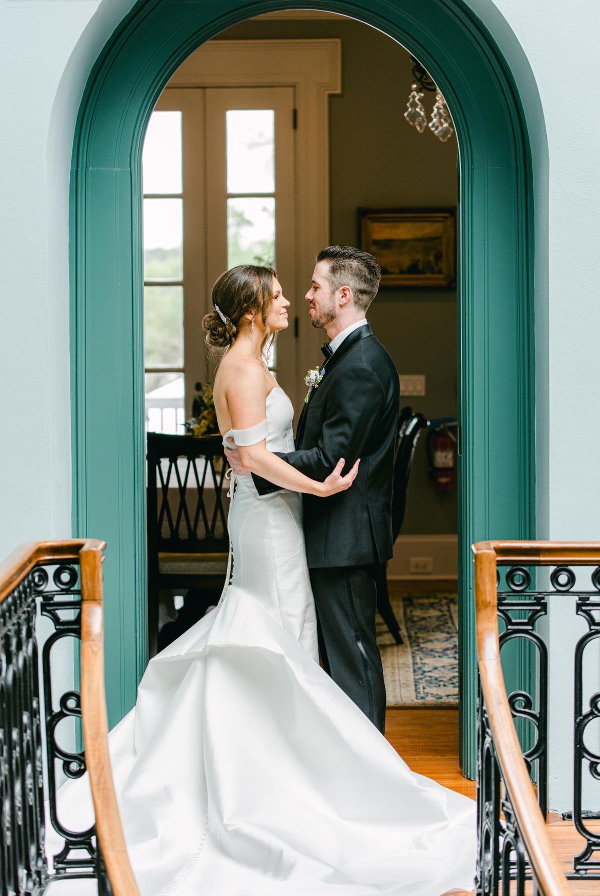 Portrait of bride and groom in front of teal arch