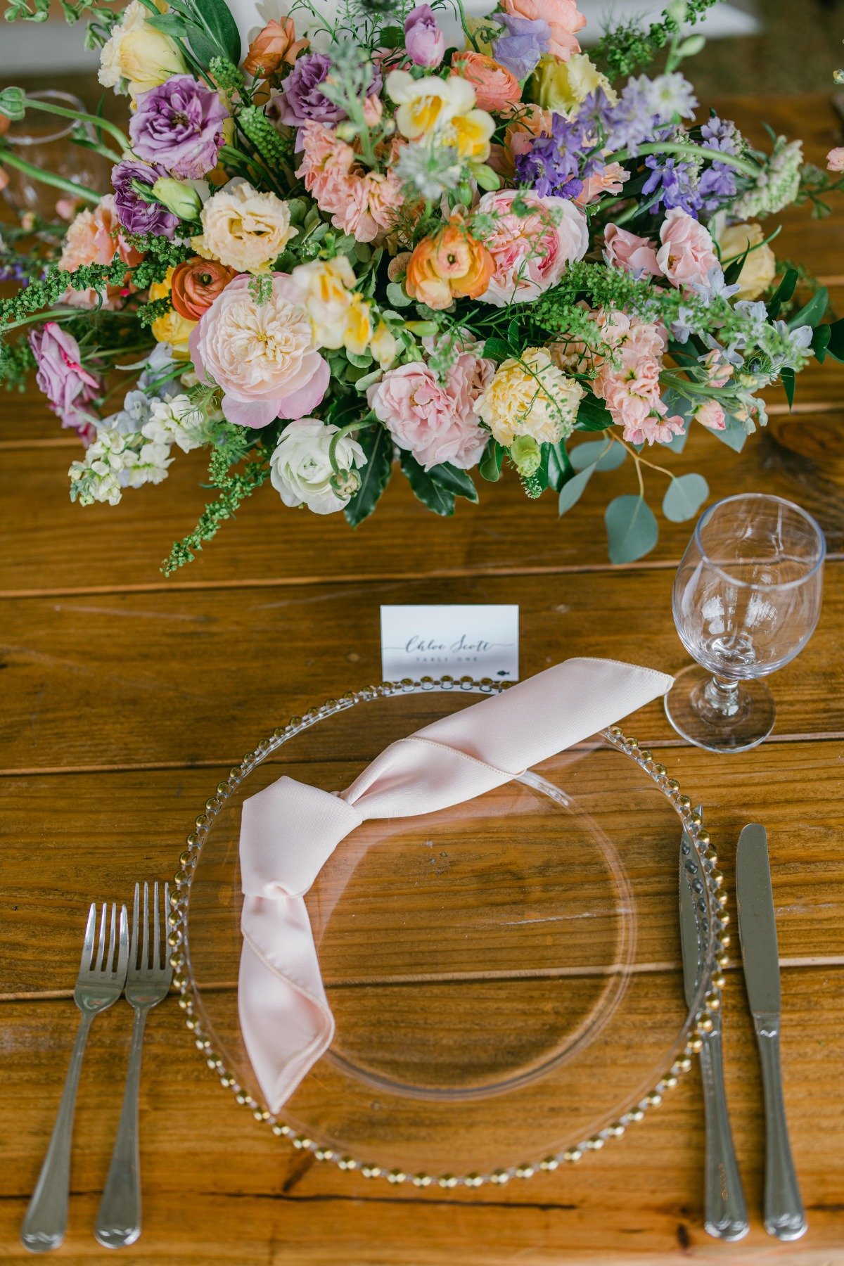 Place setting with pink napkin and centerpiece arrangement
