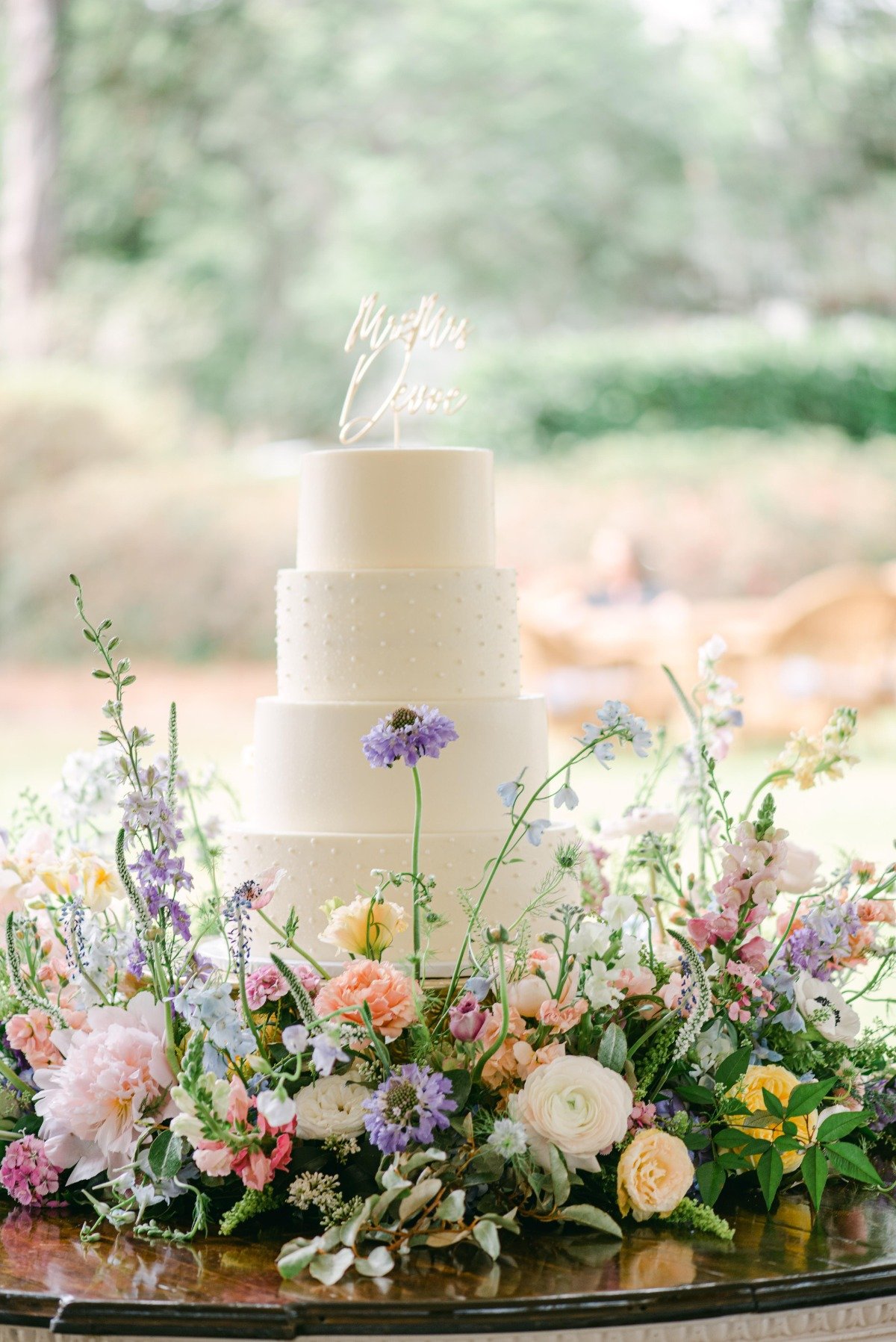 Wedding cake with cake topper and surrounded by spring flowers