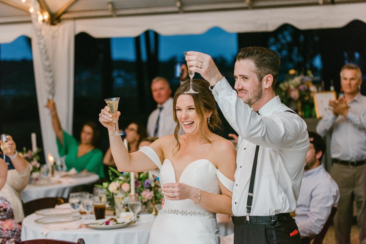 Bride and groom raising their glasses during reception