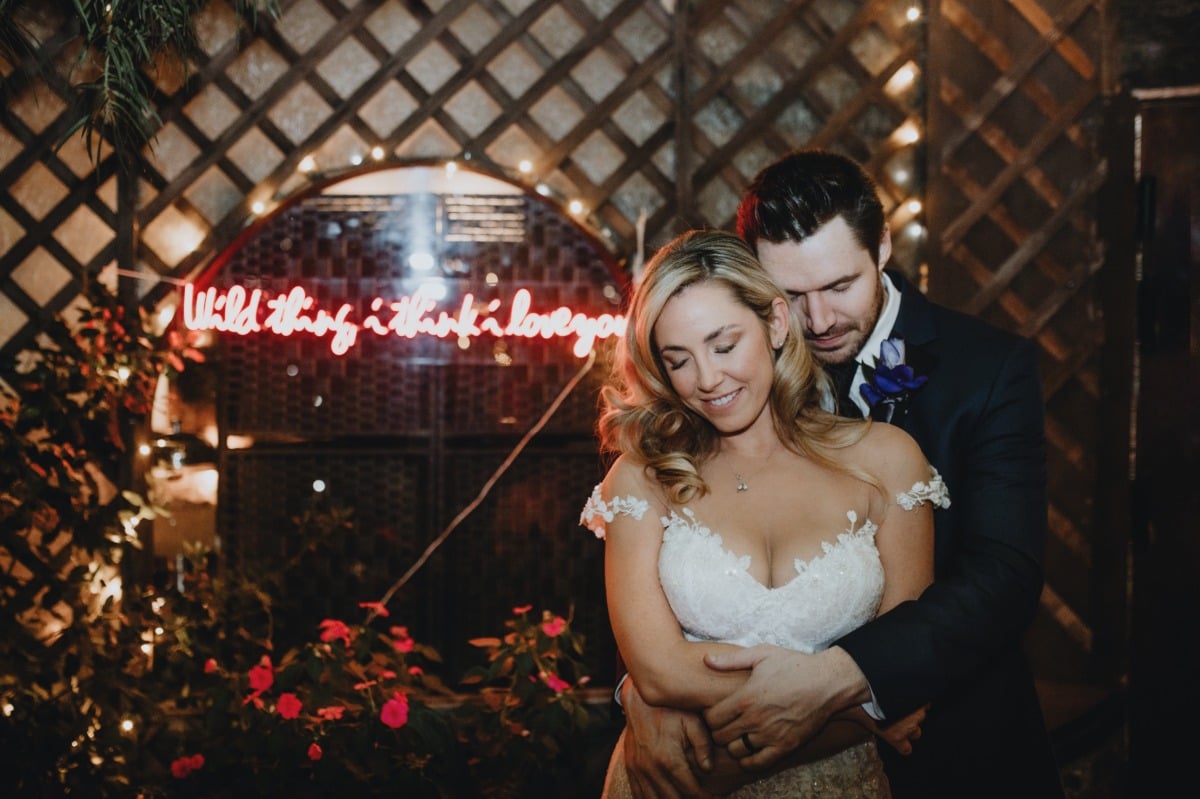 Portrait of bride and groom in front of neon sign