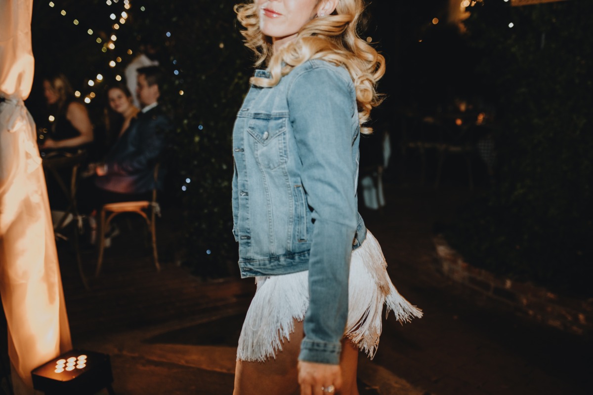 Bride in customized denim jacket and fringed party dress