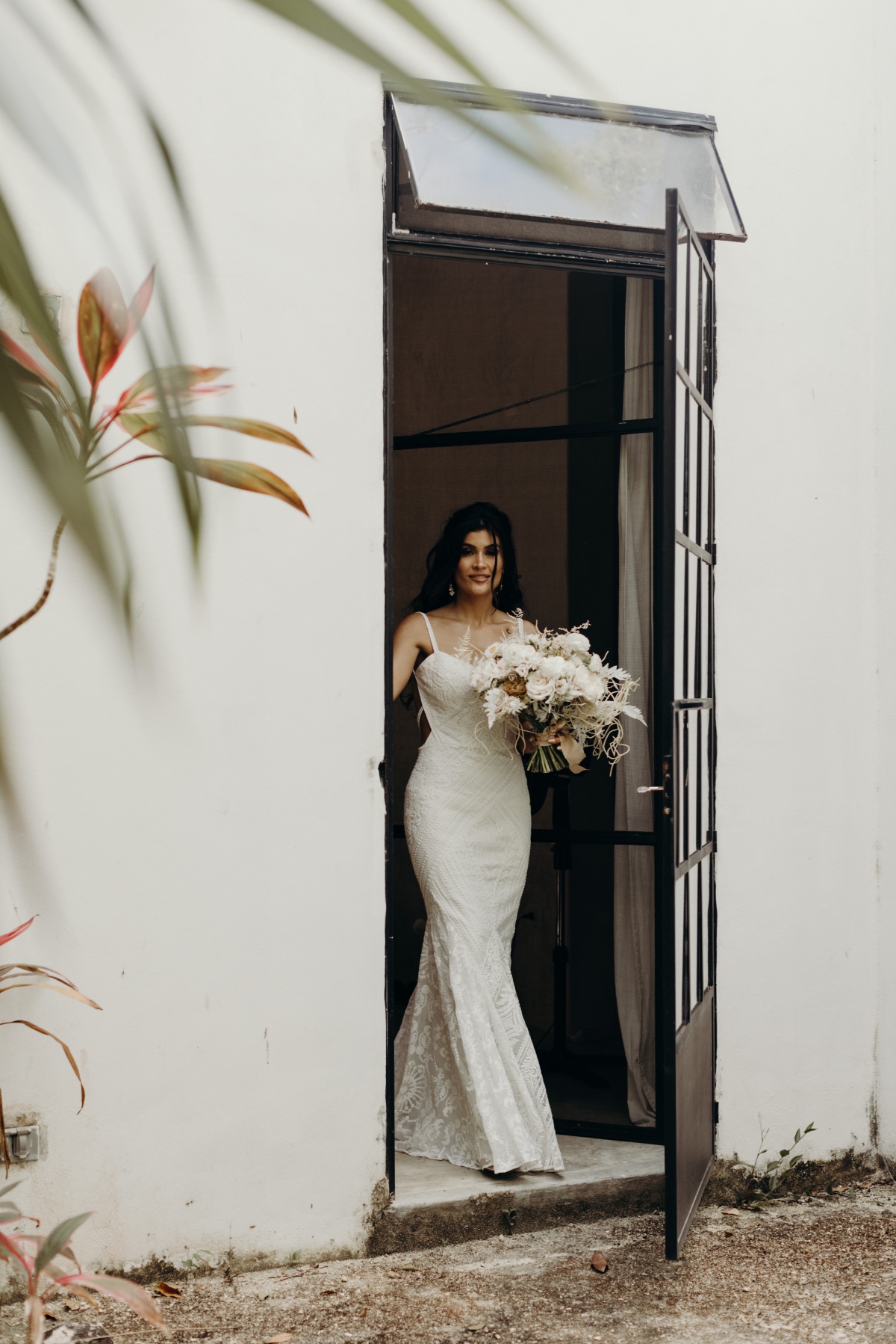 Bride exiting dressing house with bouquet