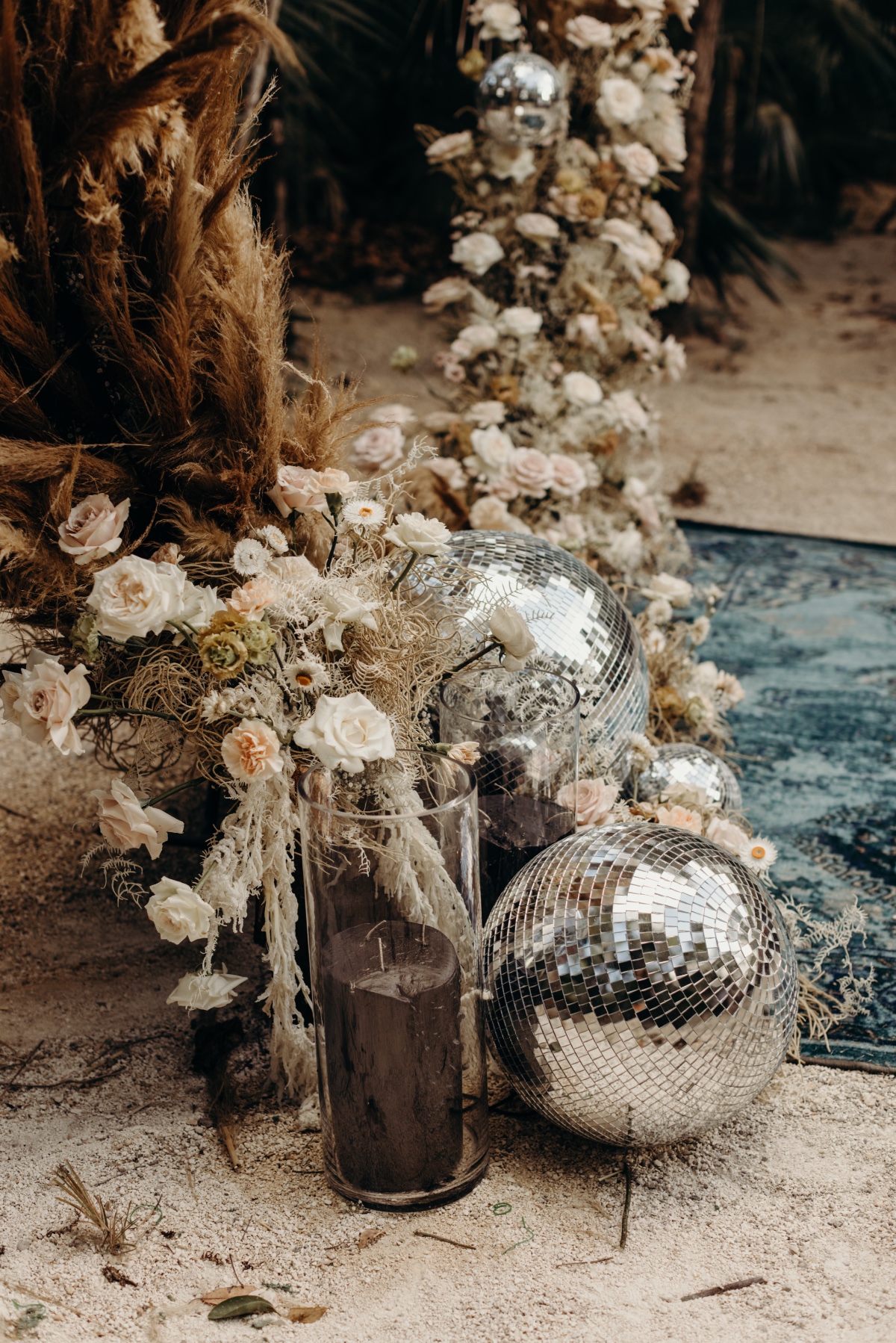 Ceremony florals with candle, disco balls, and blue carpet