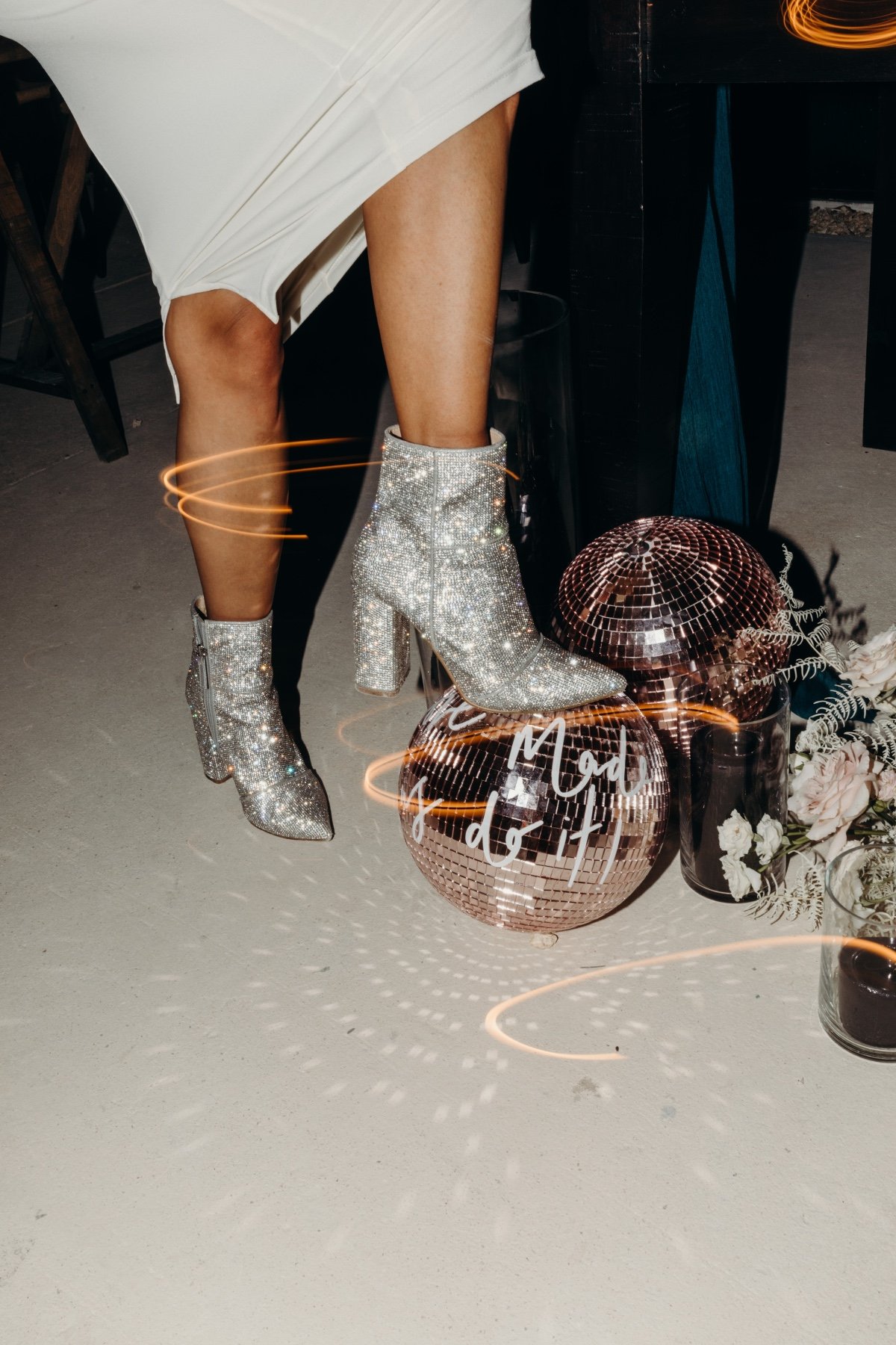 Bride stepping on disco ball in sparkly reception booties