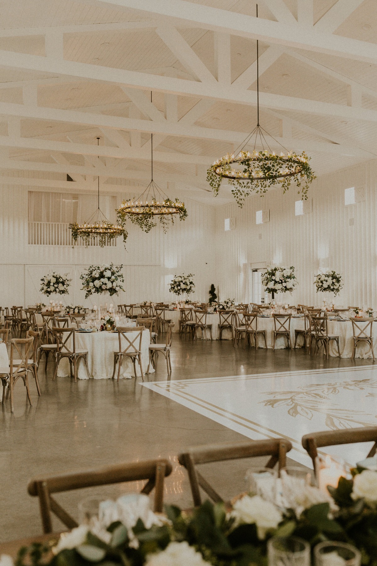Reception hall with tables and tall centerpieces and wood chairs