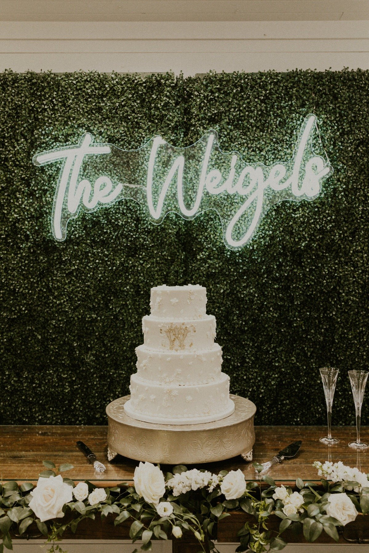 Customized neon sign behind white monogrammed wedding cake