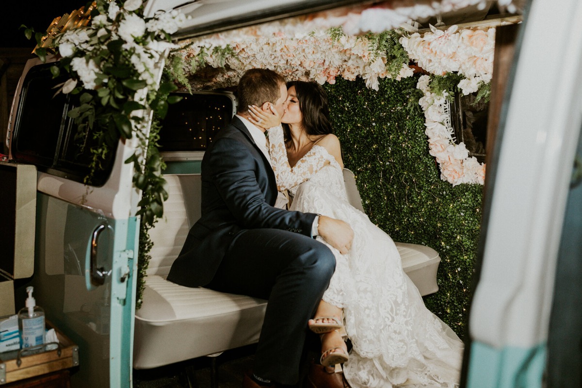 Bride and groom kissing in floral photo bus