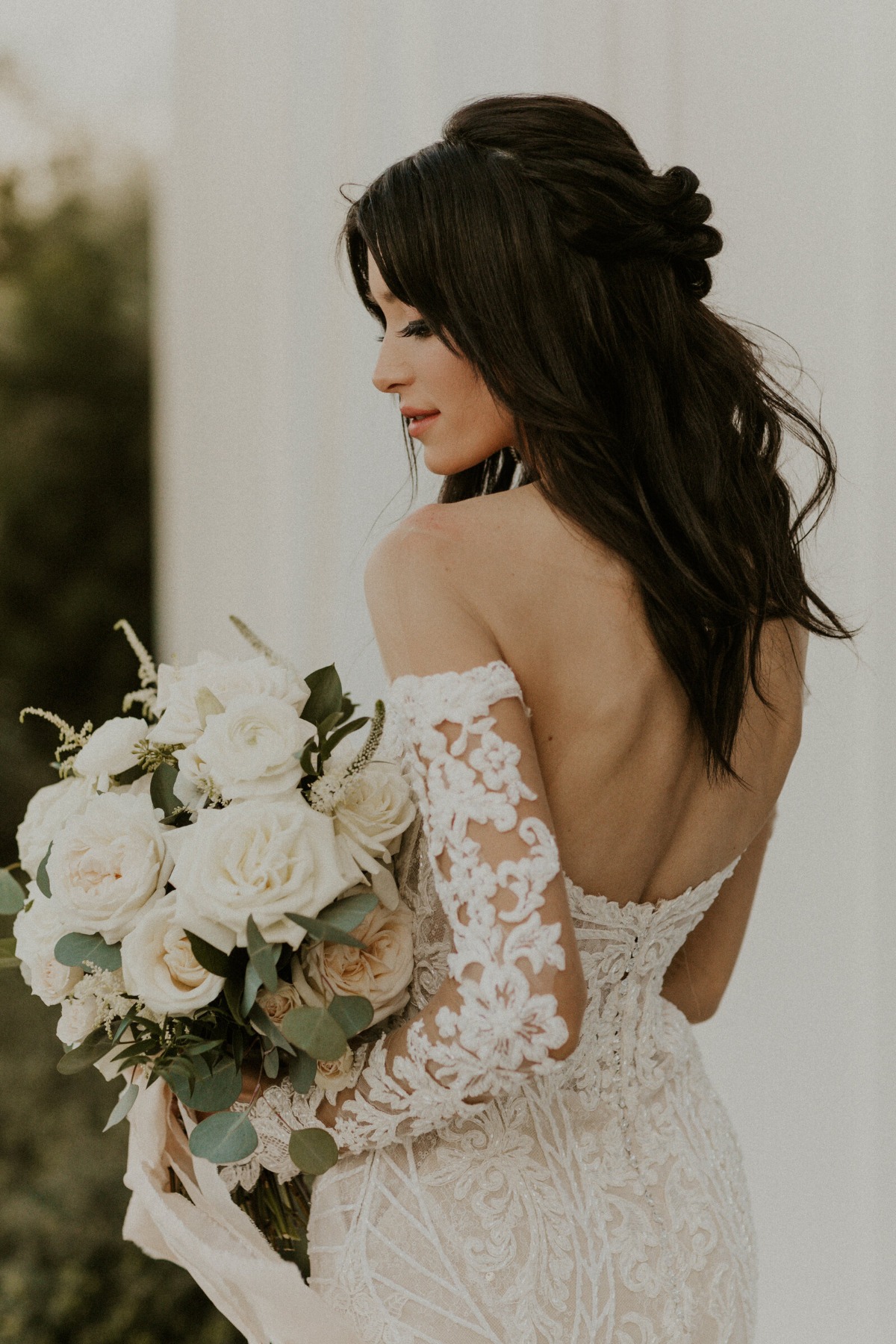 Portrait of bride facing away from camera holding bouquet