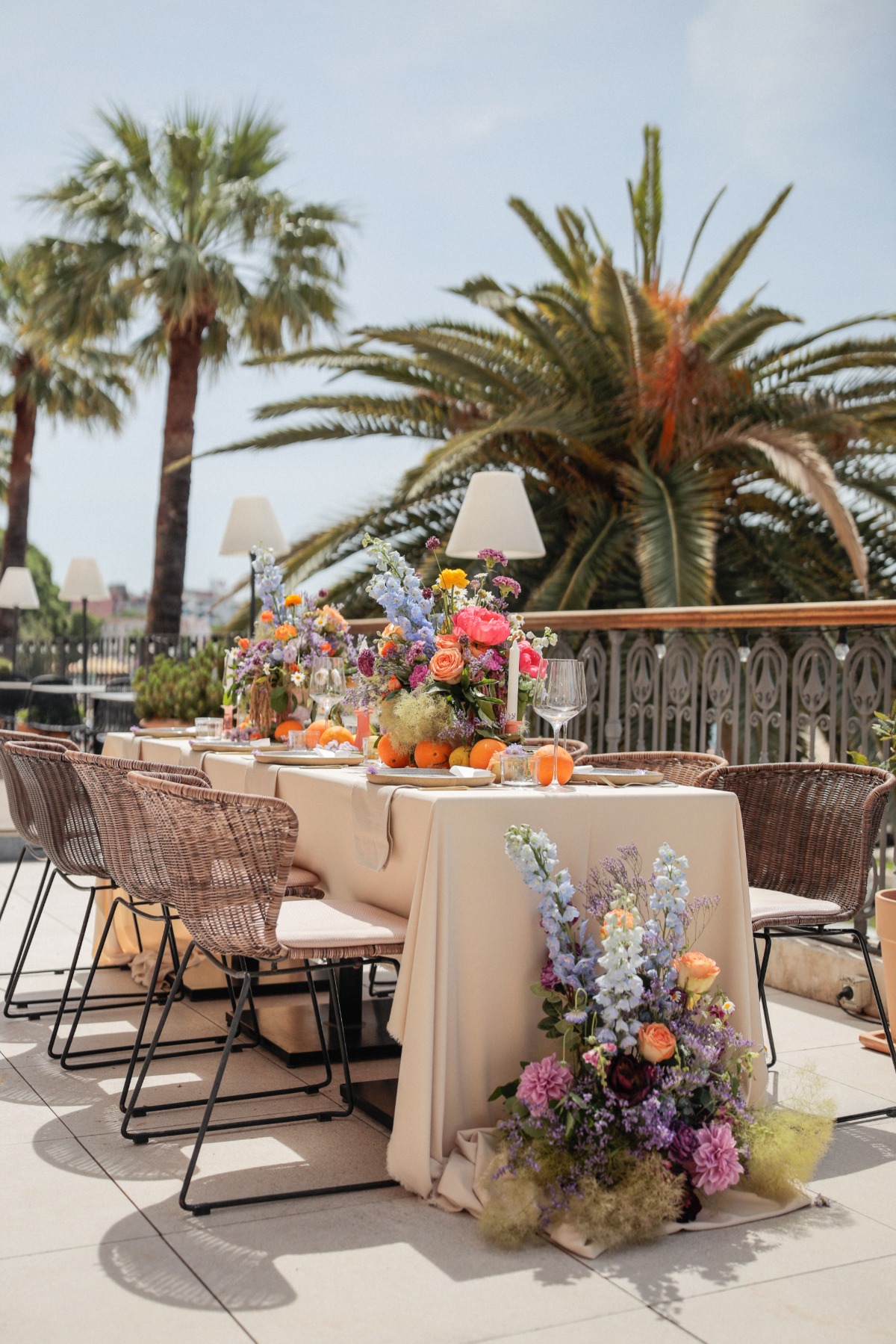 View of reception table with floral arrangements and palm trees in background
