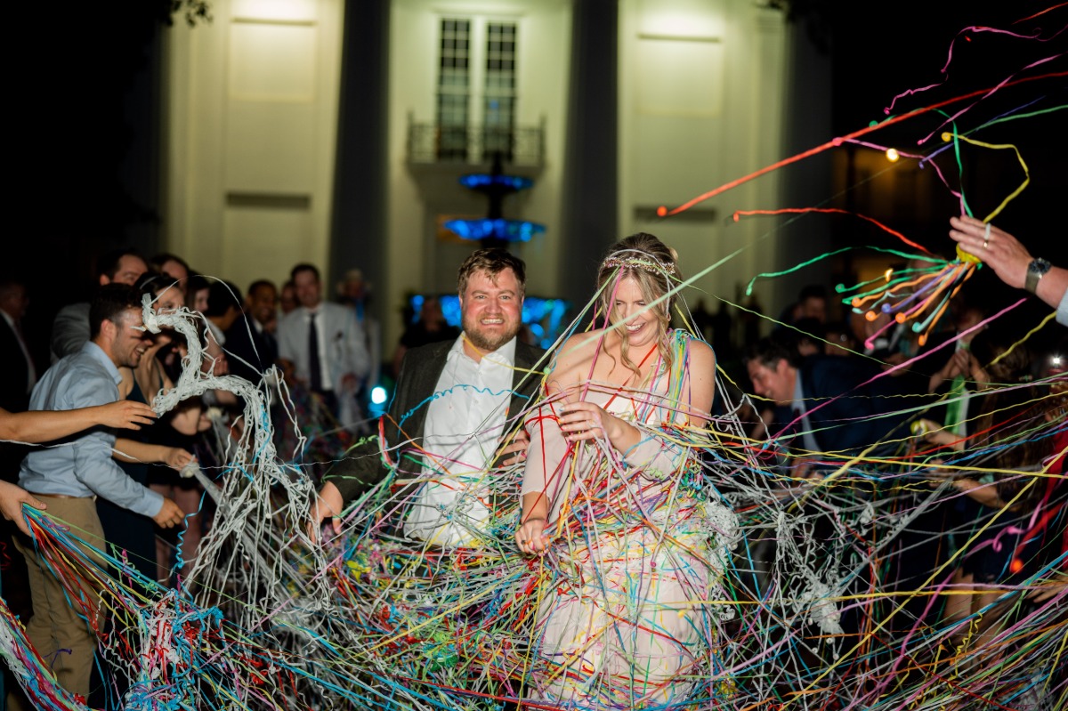Bride and groom running through rainbow silly string