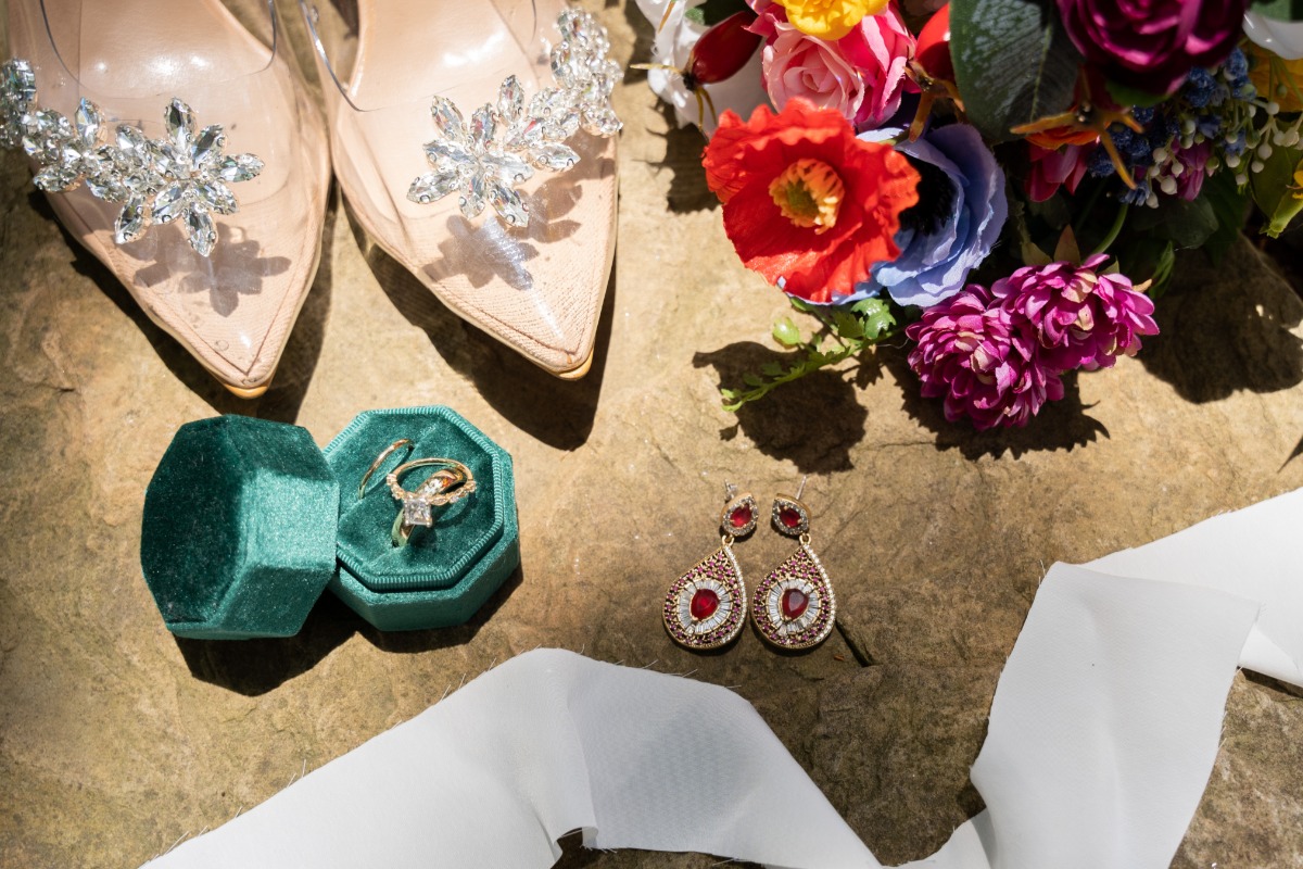 Aerial photo of wedding shoes, rings, earrings, flowers, and ribbon
