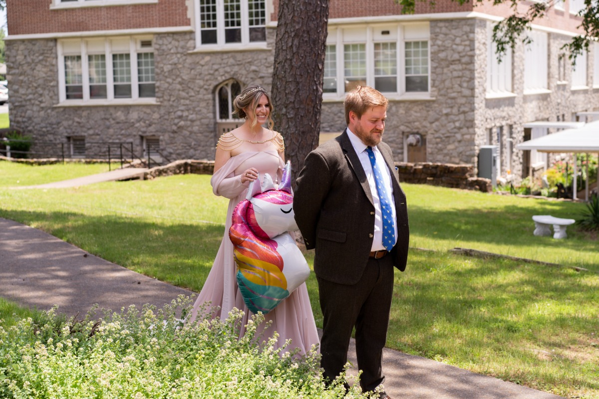 Bride walking up to groom for first look holding unicorn balloon