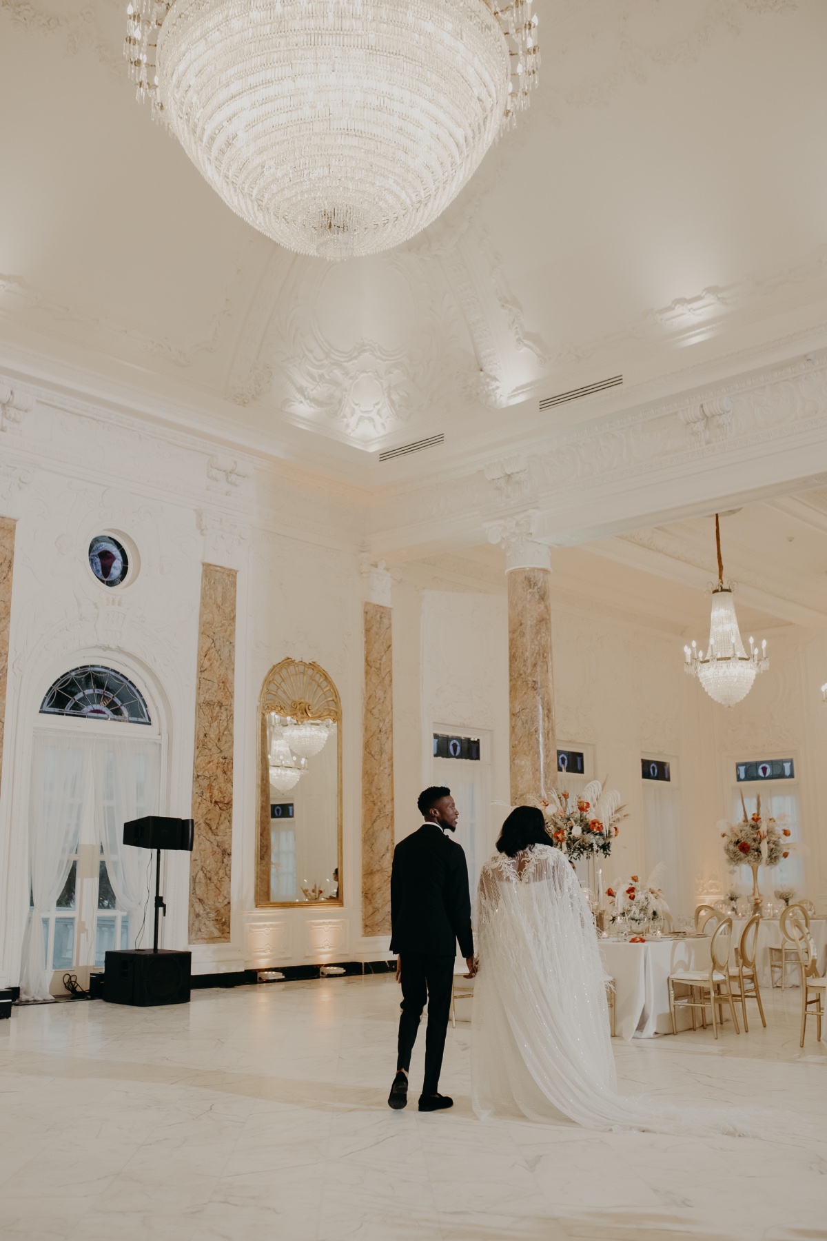 Bride and groom sneak peek of reception hall with chandelier