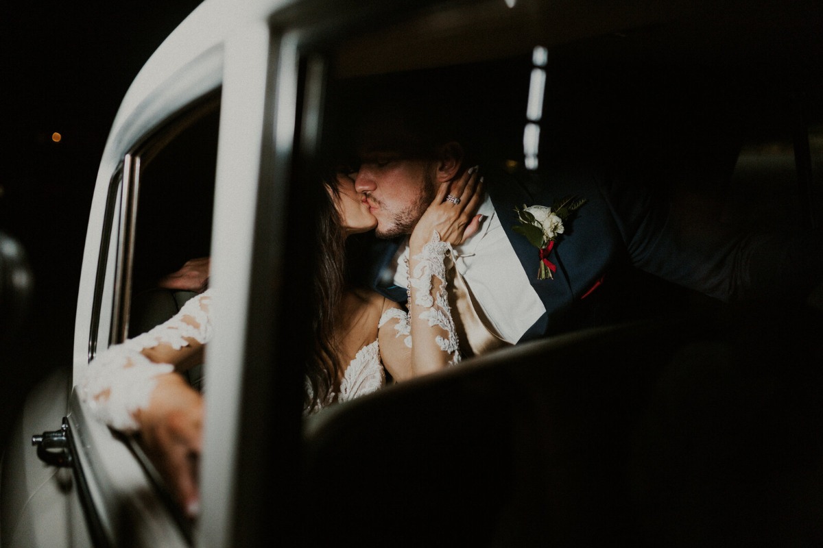 Bride and groom kissing in Rolls Royce