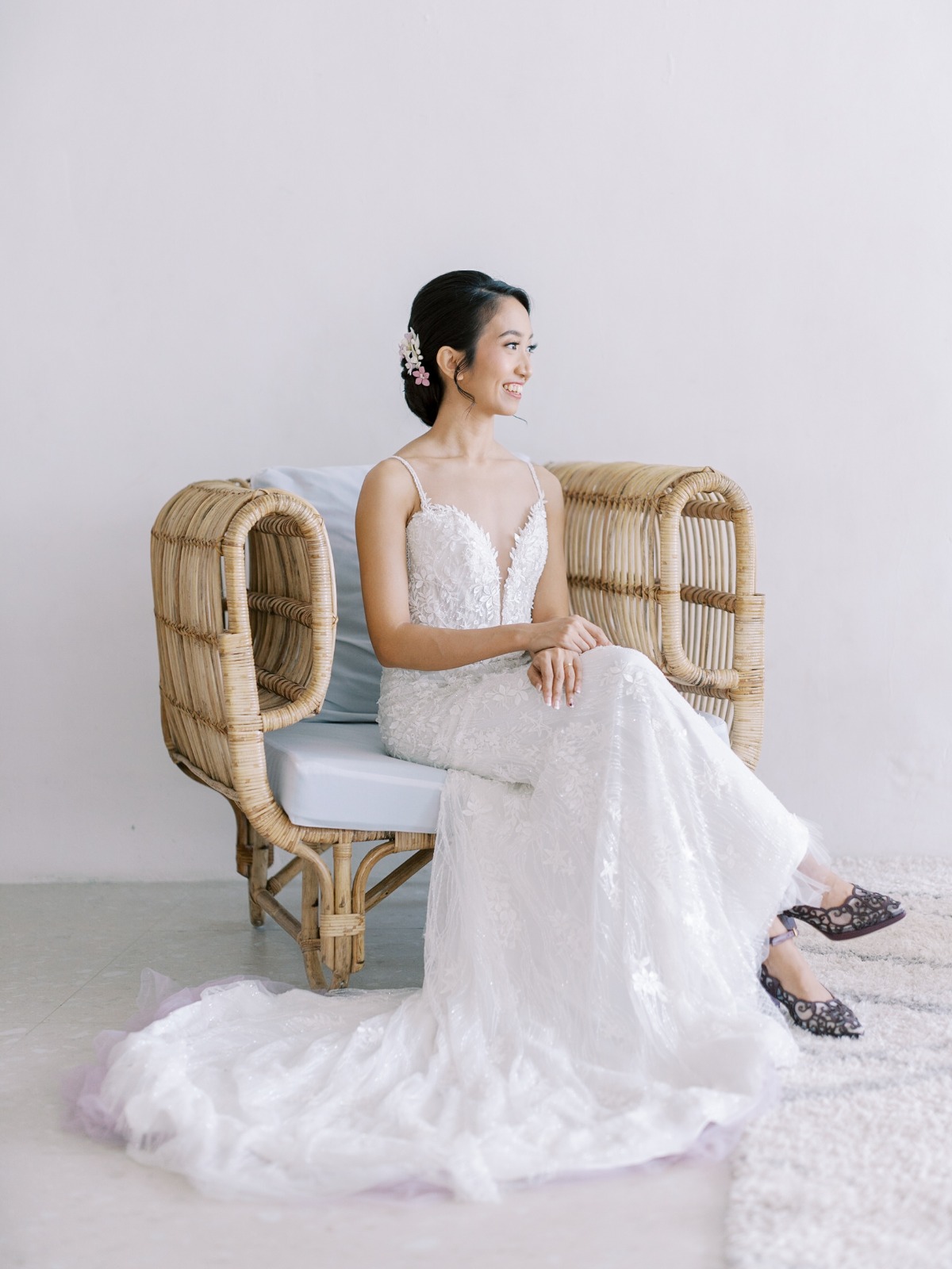 Portrait of bride sitting on wicker chair with legs crossed