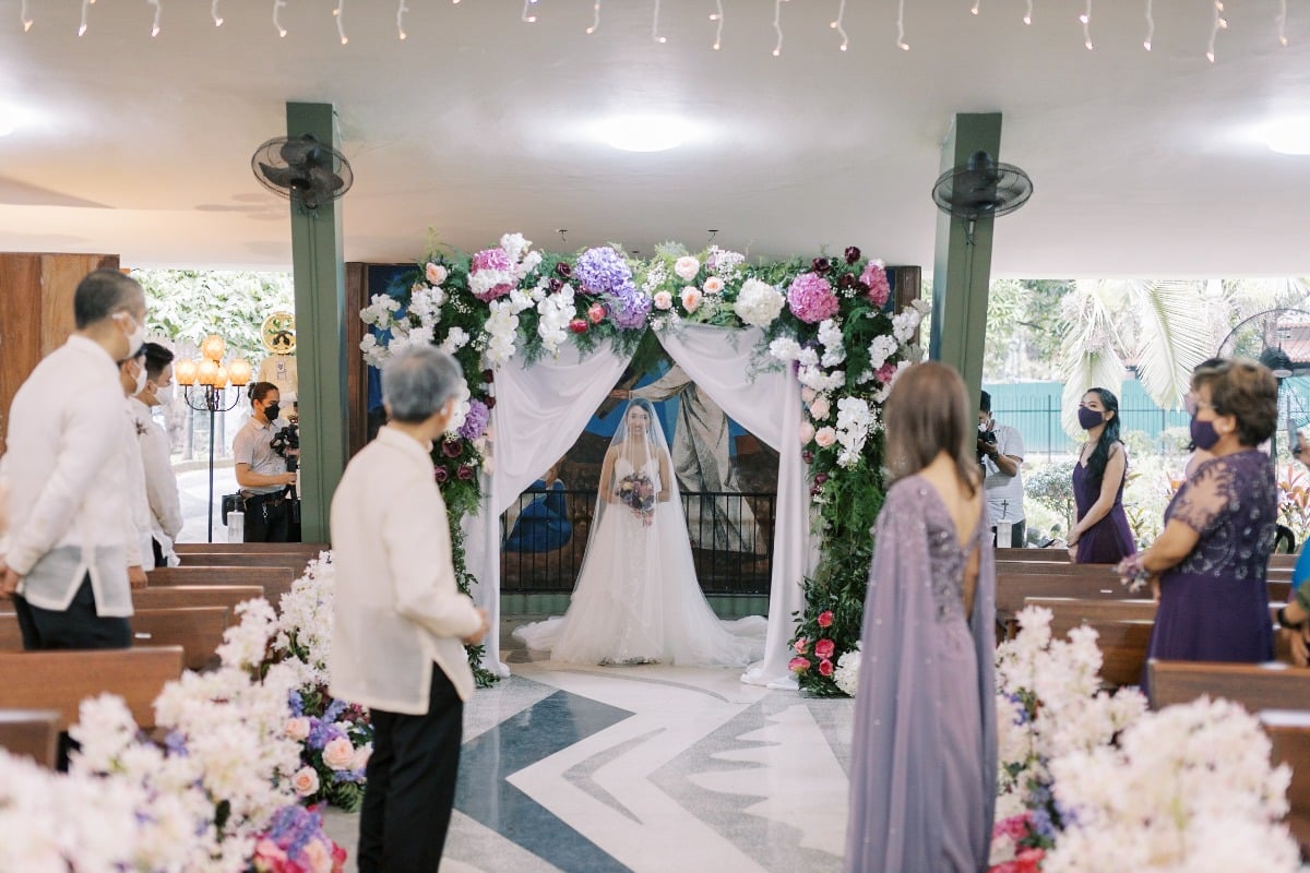 Bride entering ceremony through flower arch
