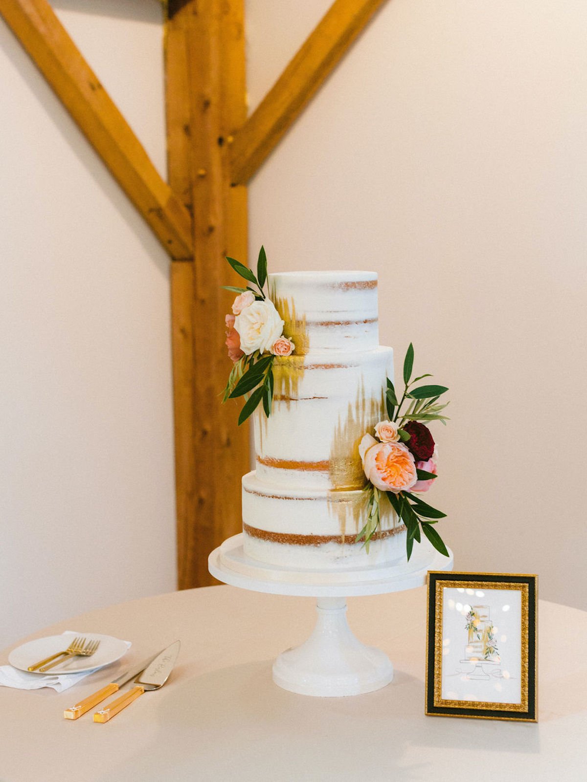Cake with floral features on table with sign and cake cutting set