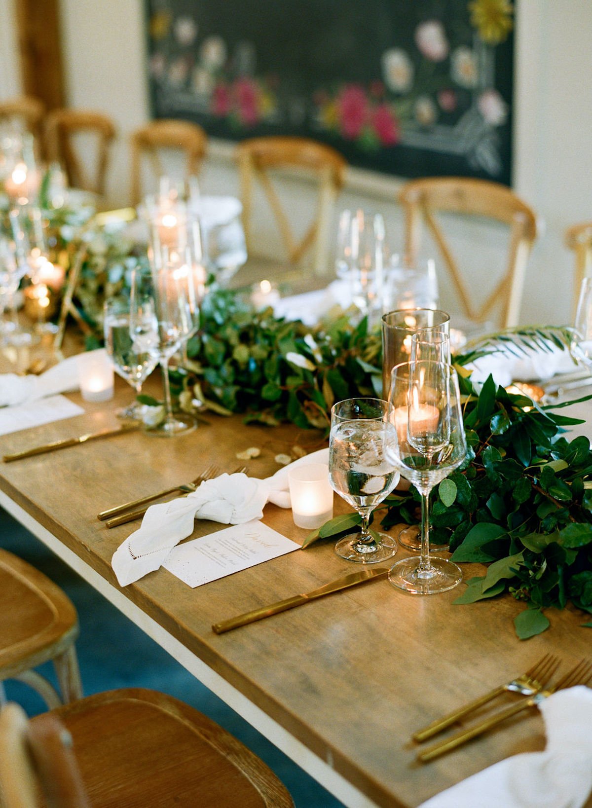 Close up of table place settings, glasses, and greenery