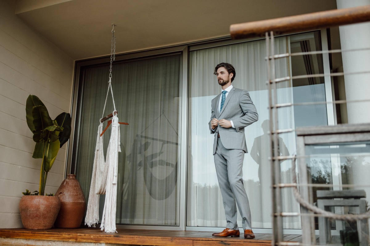 Groom standing on porch next to swing