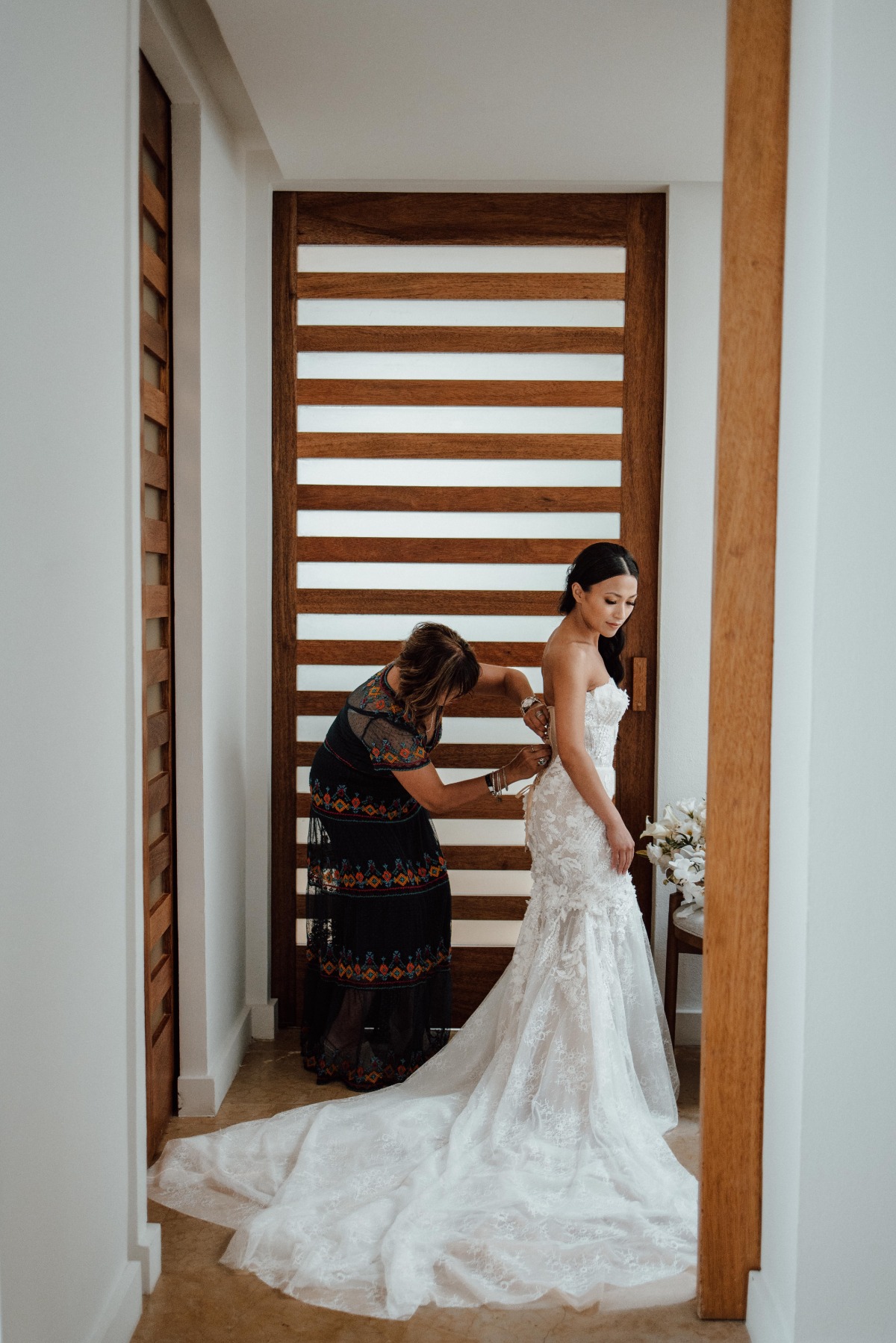 Mother of the bride buttoning bride's ceremony dress