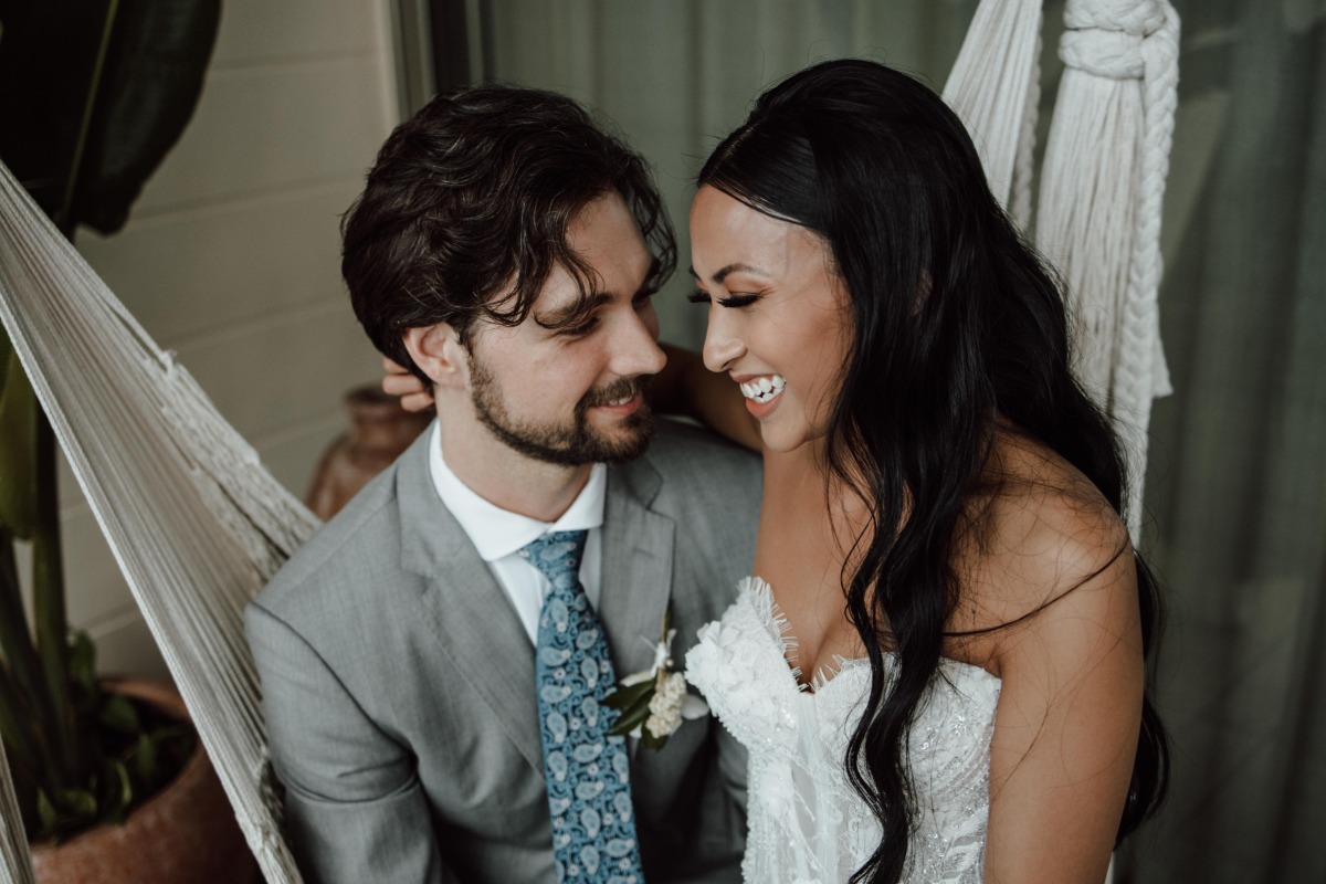 Bride and groom smiling seated on swing