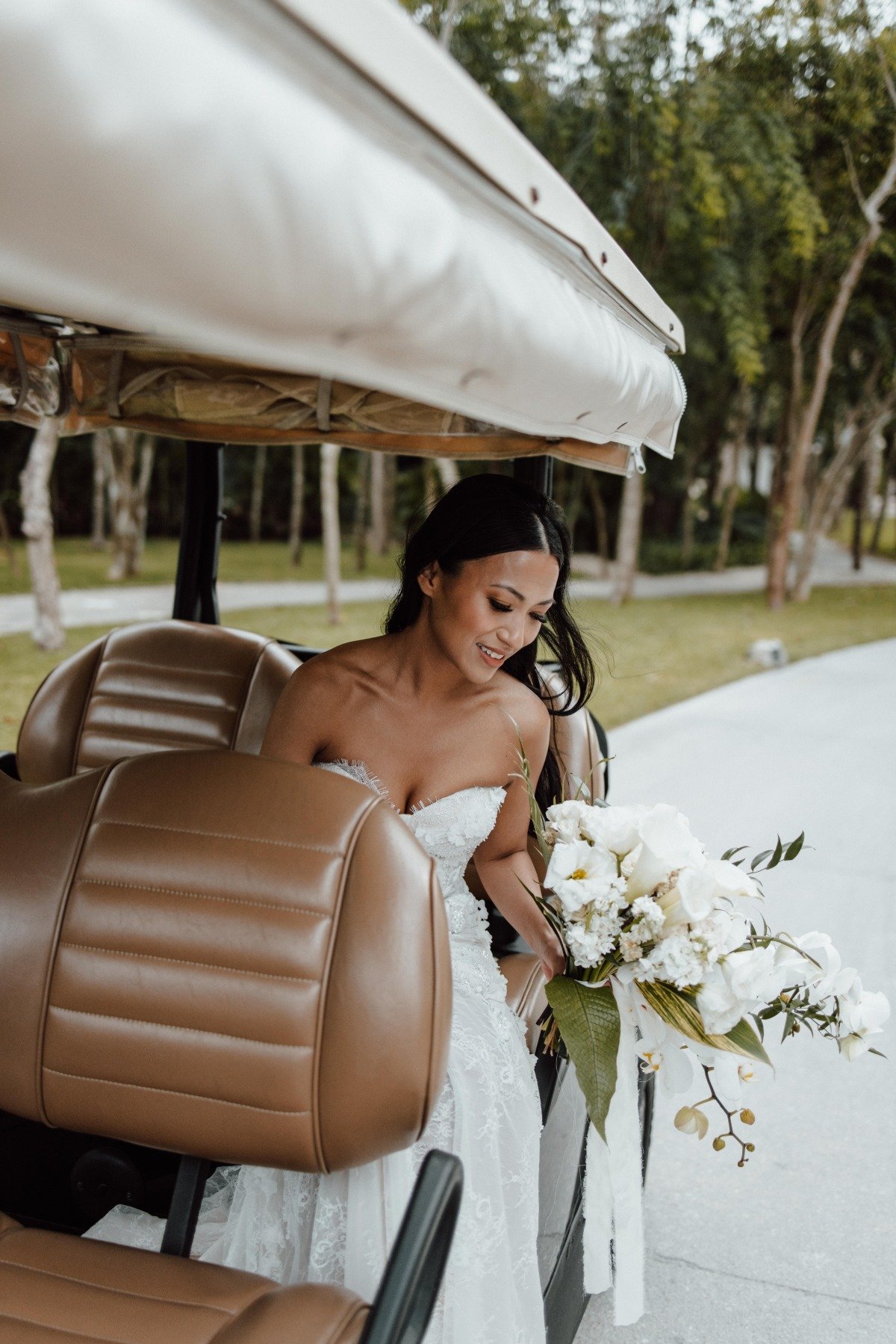 Bride holding bouquet exiting golf cart