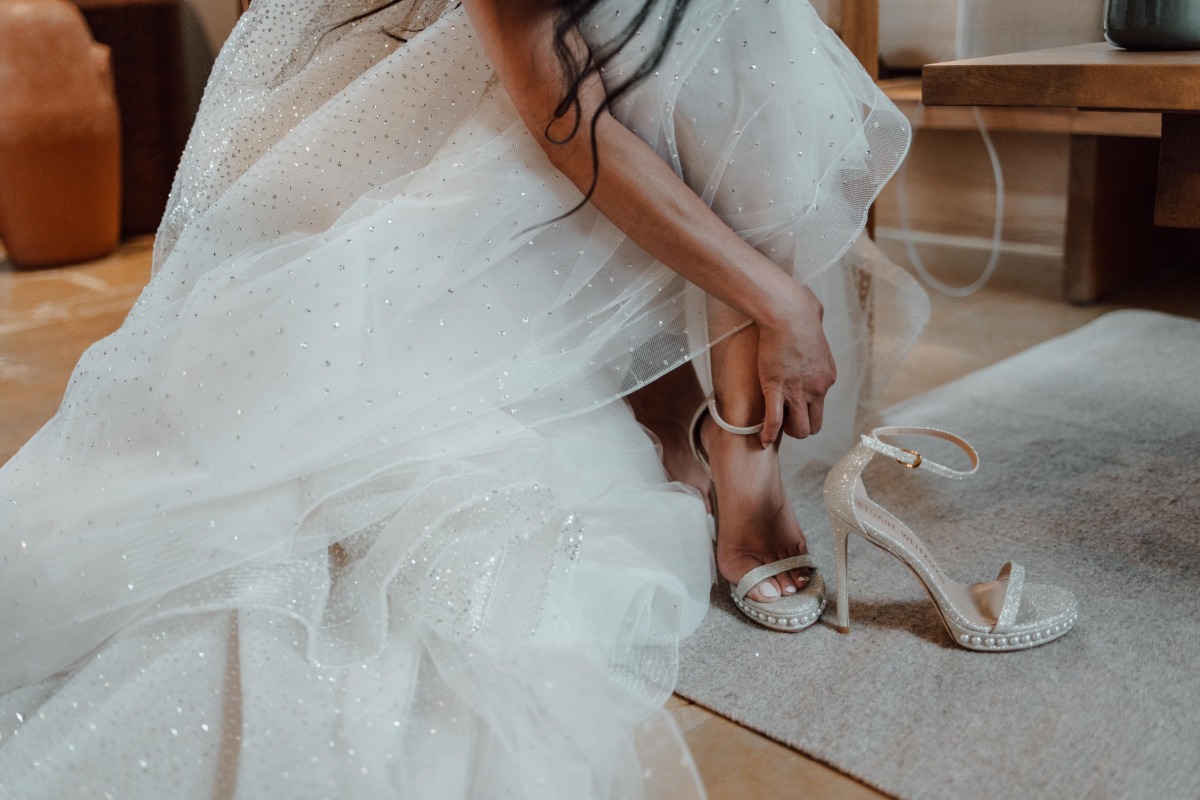 Close up of bride buckling reception shoes