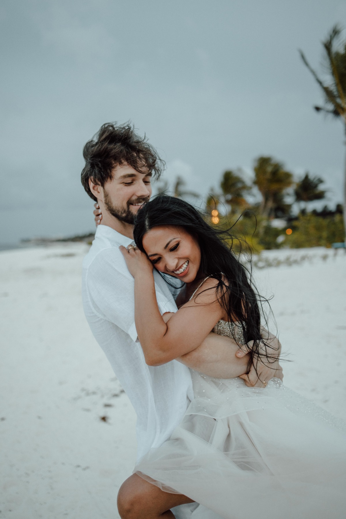 Bride jumping up on groom on beach