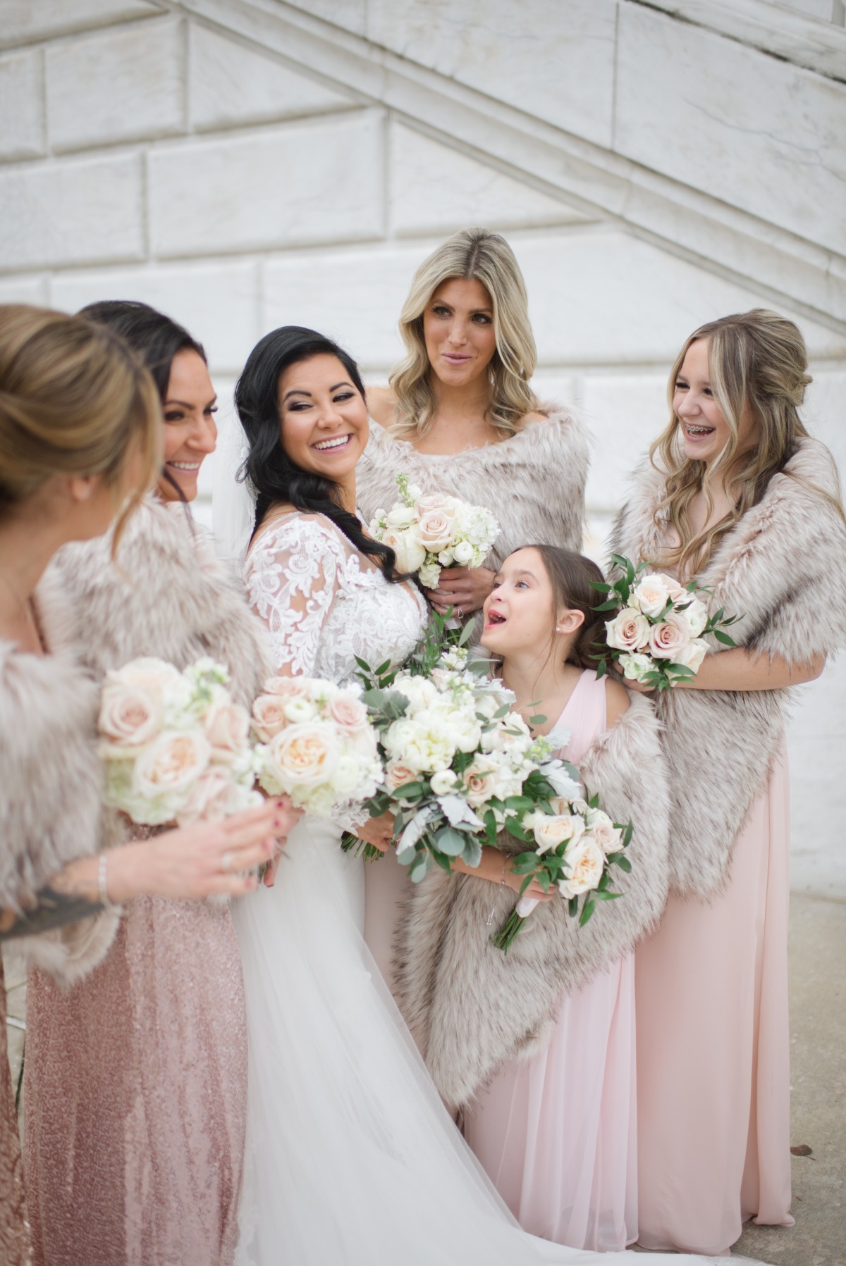 Bride with bridesmaids in fur shawls laughing together