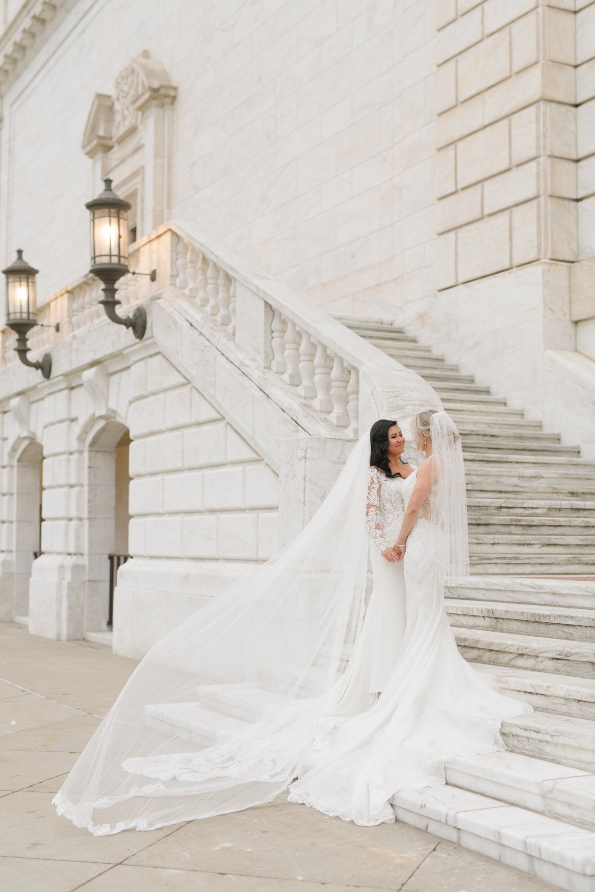 Portrait of two brides in front of cream marble steps