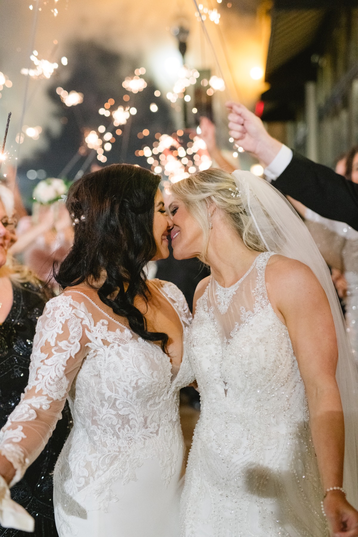 Brides kissing under sparkler exit from ceremony