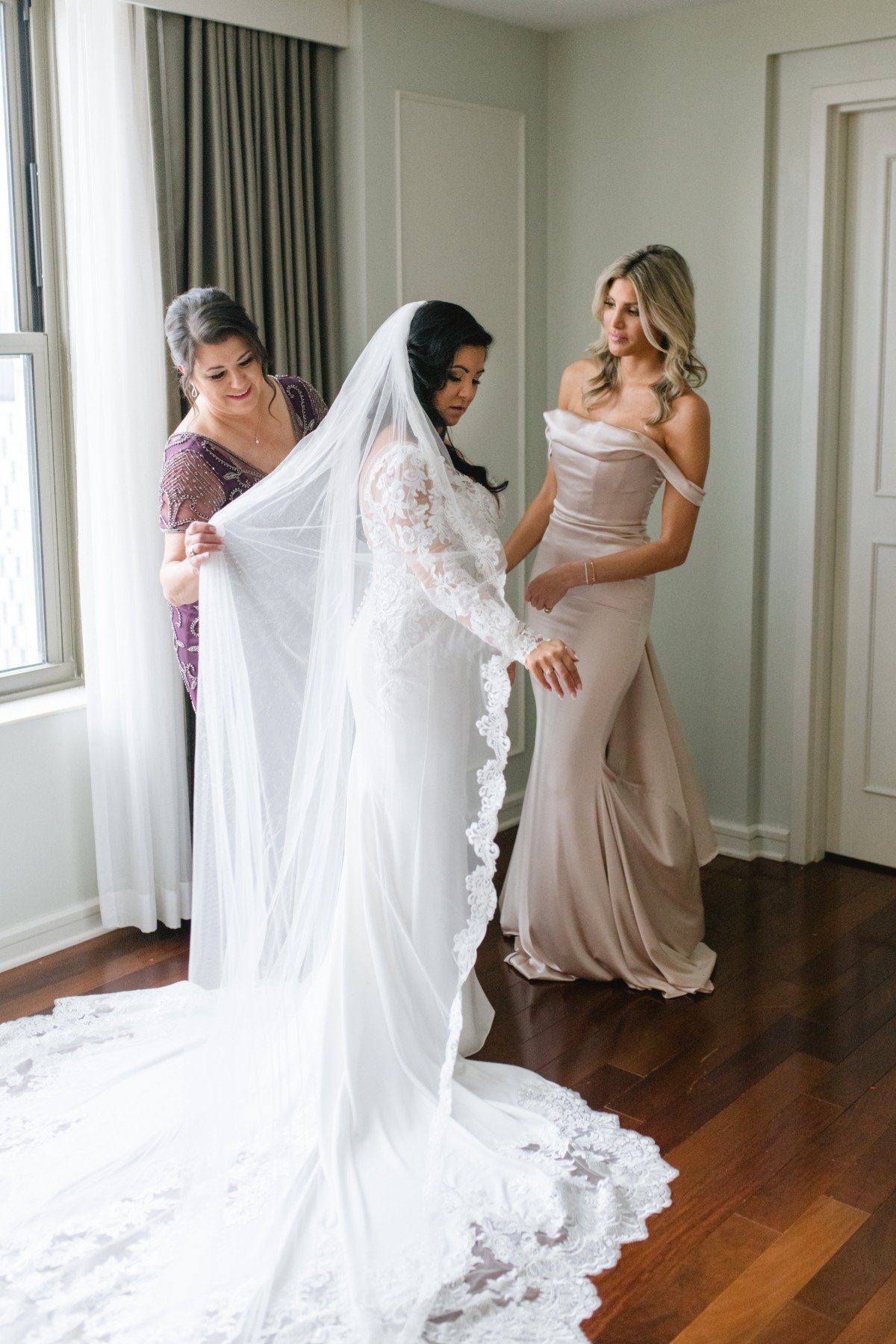 Bride's mother and bridesmaid adjusting dress and veil
