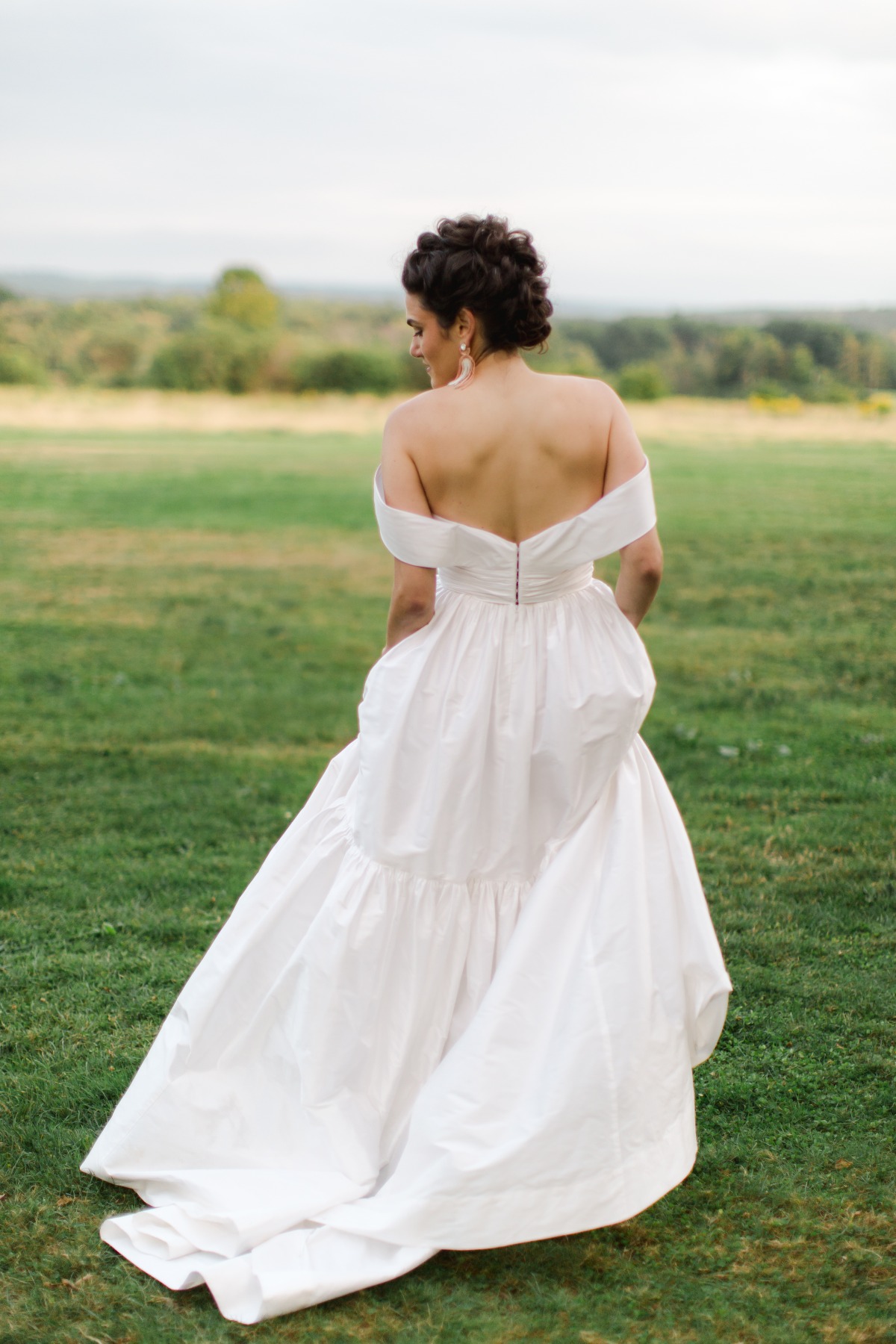 Portrait of the back of the bride's wedding dress walking away from camera in field