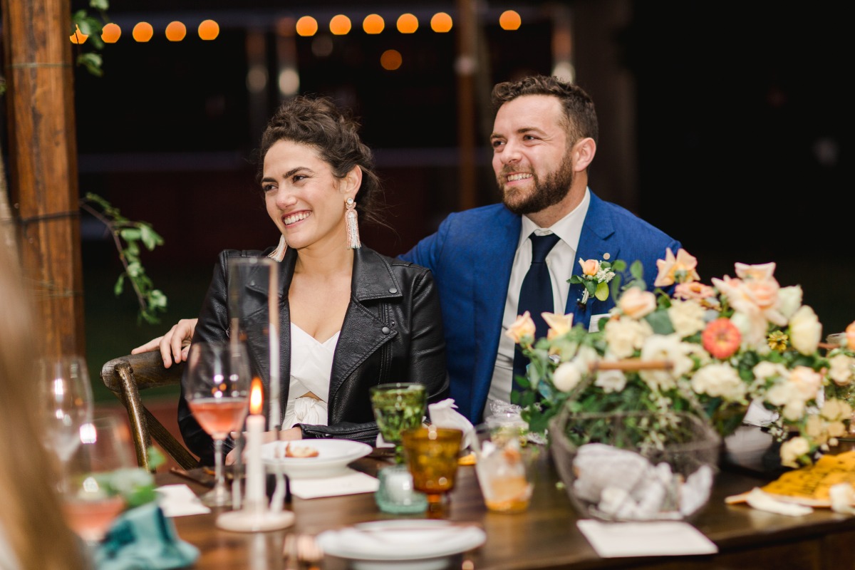 Bride in leather jacket and groom at reception table 