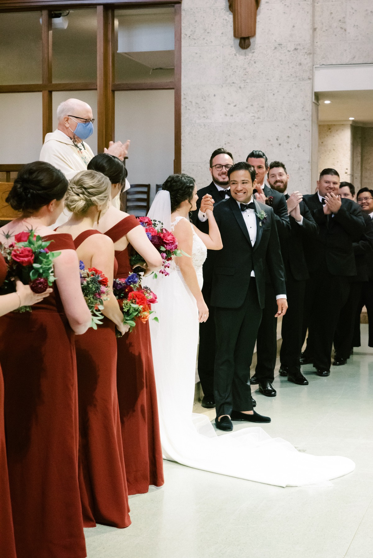 Bride and groom holding hands at wedding ceremony with wedding party surrounding them